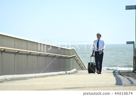 Business trip Romance gray businessman walking with carry case at seaside 44818674