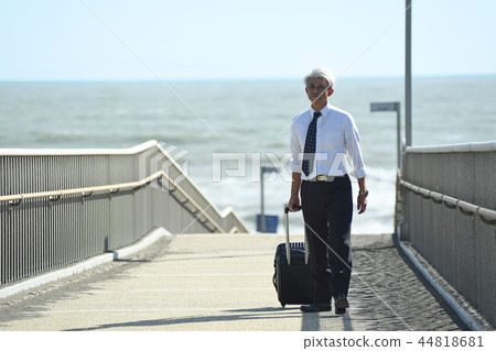 Business trip Romance gray businessman walking with carry case at seaside Business trip Romance gray businessman walking with carry case at seaside 44818681