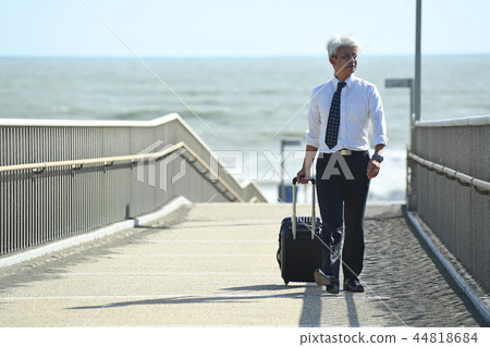 Business trip Romance gray businessman walking with carry case at seaside 44818684
