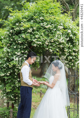 Bride and groom exchanging rings at a garden wedding 44820441