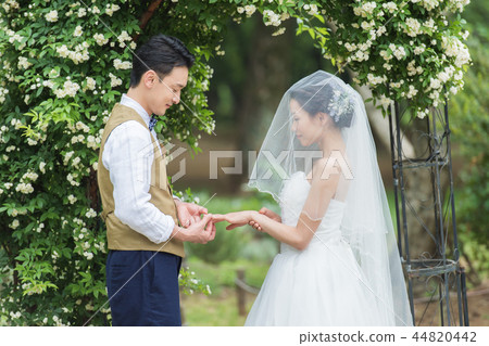 Bride and groom exchanging rings at a garden wedding 44820442