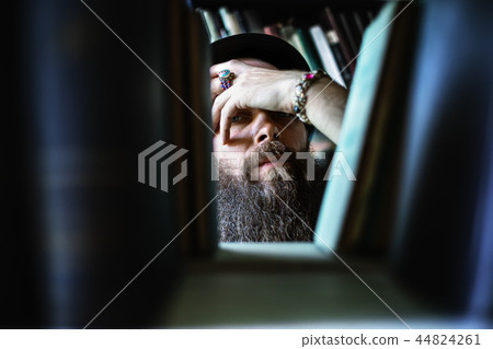 Thoughtful hipster man look through bookshelves Thoughtful hipster man look through bookshelves 44824261