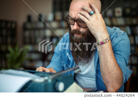 Thoughtful bearded stylish writer typing on typewriter Thoughtful bearded stylish writer typing on typewriter 44824264