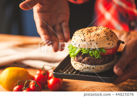 Man hand holding delicious homemade hamburger Man hand holding delicious homemade hamburger 44825076