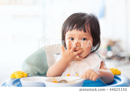 baby asian girl eating healthy food by herself 44825150