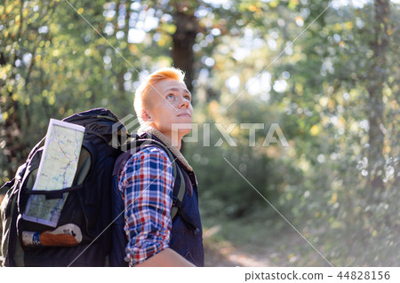 Young man enjoying hiking alone with nordic walking sticks in the forest 44828156