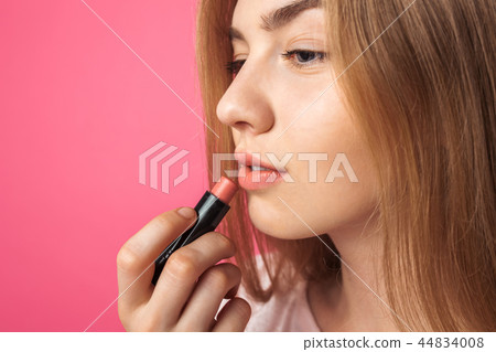 A young girl paints lips with lipstick A young girl paints lips with lipstick 44834008