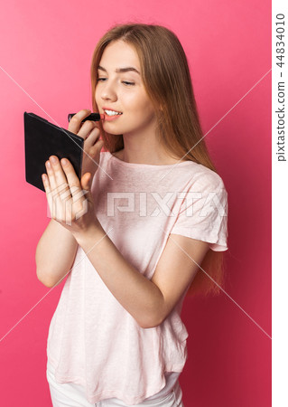 A young girl paints lips with lipstick A young girl paints lips with lipstick 44834010