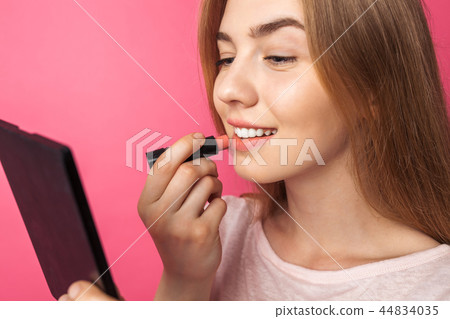 A young girl paints lips with lipstick  44834035