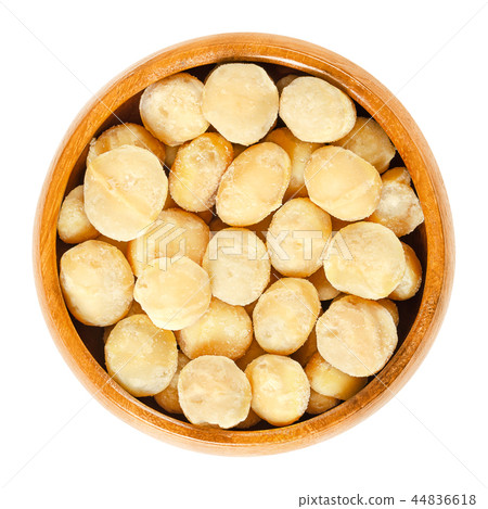 Roasted macadamia nuts in wooden bowl over white 44836618