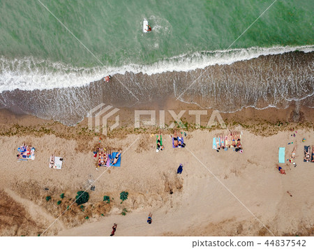 People rest on the wild beach with their families. 44837542