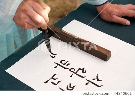 A hand writing a brush stroke 44840661