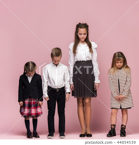Cute stylish children on pink studio background. The beautiful teen girls and boy standing together 44854539