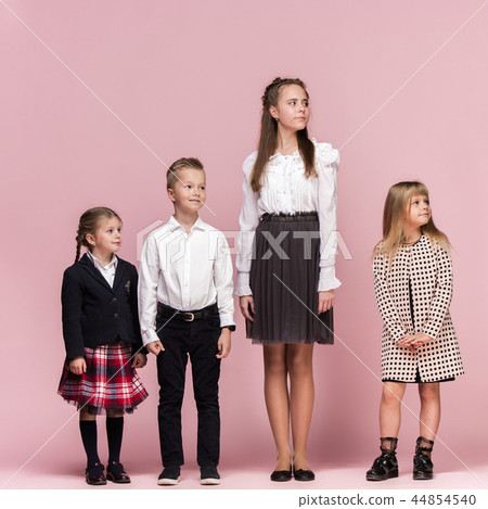 Cute stylish children on pink studio background. The beautiful teen girls and boy standing together 44854540