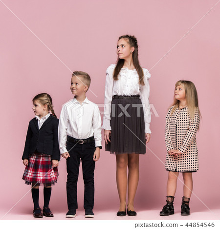 Cute stylish children on pink studio background. The beautiful teen girls and boy standing together 44854546