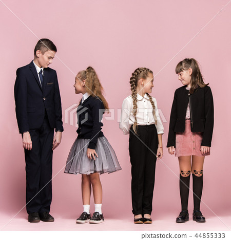 Cute stylish children on pink studio background. The beautiful teen girls and boy standing together Cute stylish children on pink studio background. The beautiful teen girls and boy standing together 44855333