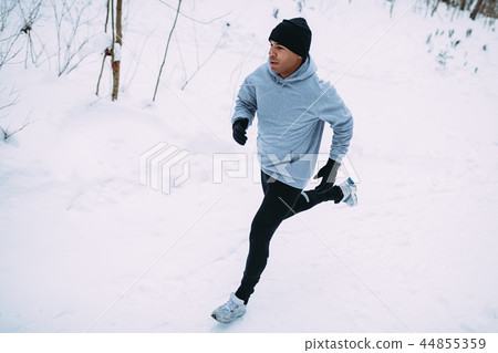 Top view of young man running in snow forest Top view of young man running in snow forest 44855359
