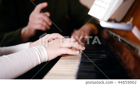 An old teacher teaching little girl how to play piano An old teacher teaching little girl how to play piano 44859002