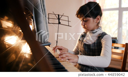 A little girl playing piano on music lesson. Beautiful sunlight 44859042