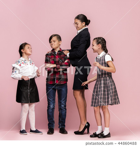 Cute stylish children on pink studio background. The beautiful teen girls and boy standing together Cute stylish children on pink studio background. The beautiful teen girls and boy standing together 44860488