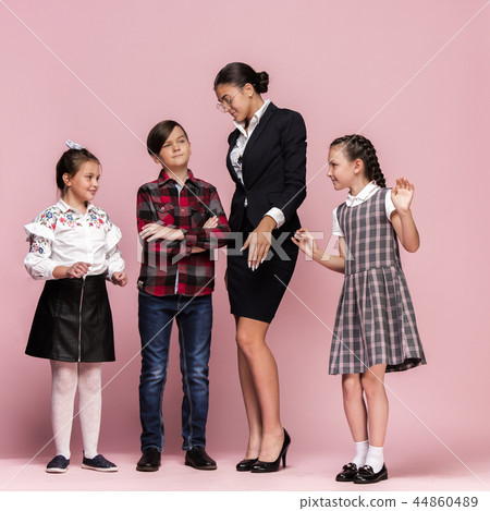 Cute stylish children on pink studio background. The beautiful teen girls and boy standing together Cute stylish children on pink studio background. The beautiful teen girls and boy standing together 44860489