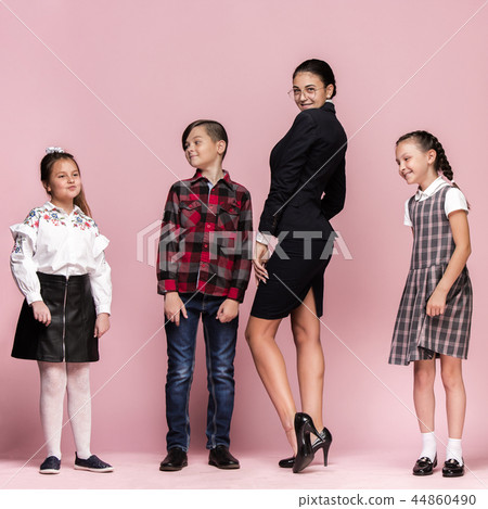 Cute stylish children on pink studio background. The beautiful teen girls and boy standing together Cute stylish children on pink studio background. The beautiful teen girls and boy standing together 44860490