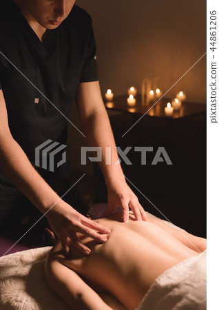 Men's hands make a therapeutic neck massage for a girl lying on a massage couch in a massage spa Men's hands make a therapeutic neck massage for a girl lying on a massage couch in a massage spa 44861206