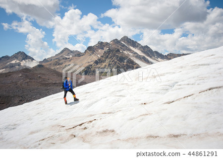 Traveler in a cap and sunglasses with a backpack on his shoulders in the snowy mountains on the Traveler in a cap and sunglasses with a backpack on his shoulders in the snowy mountains on the 44861291