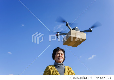 Senior woman receiving luggage with drone Senior woman receiving luggage with drone 44863095