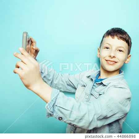 little cute boy posing emotional on blue background with smartph 44866898