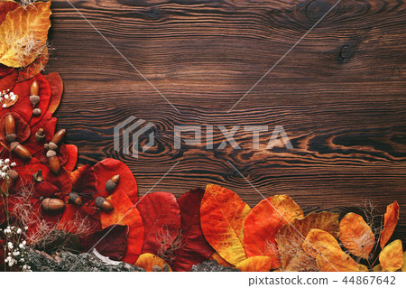 autumn leaves, acorns and flowers on wooden background 44867642