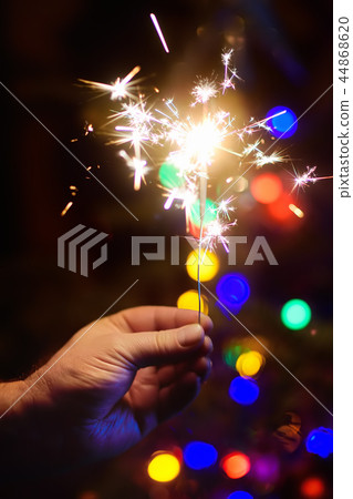 Bright sparkler with Christmas tree on background Bright sparkler with Christmas tree on background 44868620