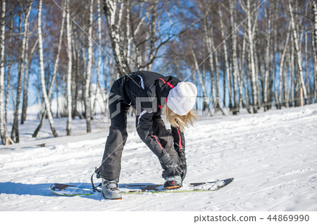 Young adult woman snowboarder standing on board Young adult woman snowboarder standing on board 44869990