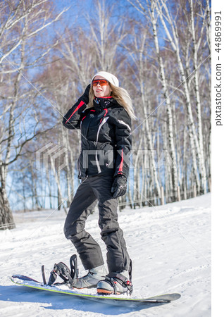 Young adult woman snowboarder standing on board Young adult woman snowboarder standing on board 44869991