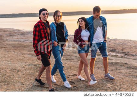 friends on beach together walking during sunset friends on beach together walking during sunset 44870528