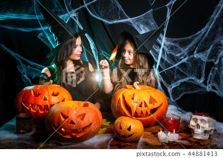 Happy Halloween . Beautiful caucasian mother and her daughter in witch costumes enjoy using magic Happy Halloween . Beautiful caucasian mother and her daughter in witch costumes enjoy using magic 44881413