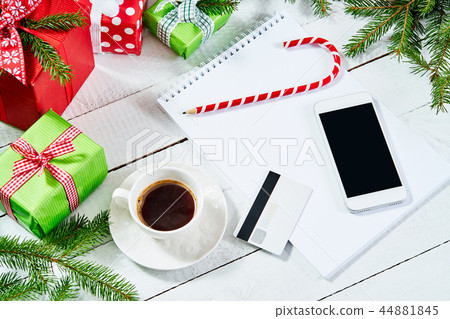 top view on the phone and a piece of paper on an wooden table with Christmas decorations top view on the phone and a piece of paper on an wooden table with Christmas decorations 44881845