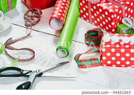 colorful papers for wrapping Christmas gifts and scissors on a white wooden table 44881863