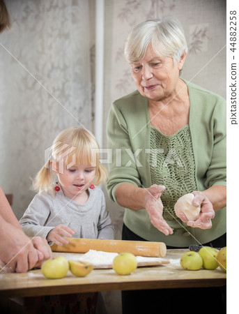 A grandmother and a granddaughter are making little pies A grandmother and a granddaughter are making little pies 44882258