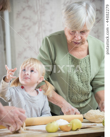 An old lady making little pies with a blonde little girl An old lady making little pies with a blonde little girl 44882279