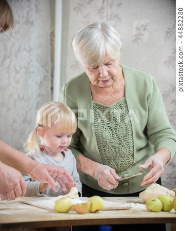 An old lady making little pies with a little girl 44882280