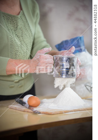 An old lady making little pies. Sift flour An old lady making little pies. Sift flour 44882318