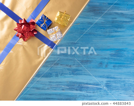Top view of golden christmas gift boxes on old vintage blue wooden background Top view of golden christmas gift boxes on old vintage blue wooden background 44883843
