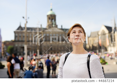 Mature woman standing on a Sunny autumn day in the Central dam square in the old city of Amsterdam. 44887214