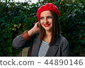 Fixing hair under red beret. 44890146