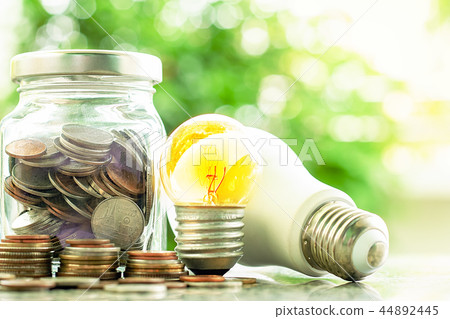 Glowing light bulb with coins in the glass jar 44892445