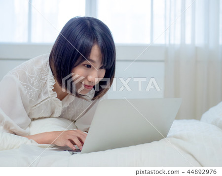 婦女在床上的操作一台計算機 44892976