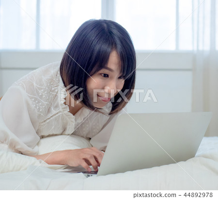 婦女在床上的操作一台計算機 44892978