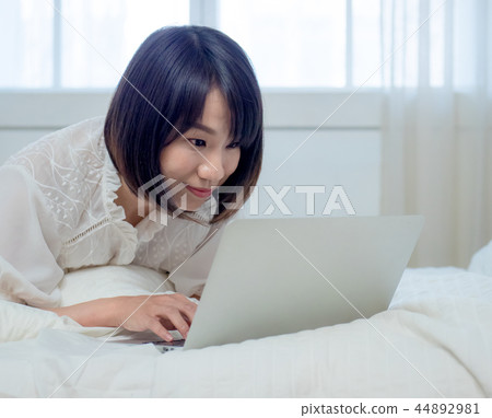 婦女在床上的操作一台計算機 婦女在床上的操作一台計算機 44892981