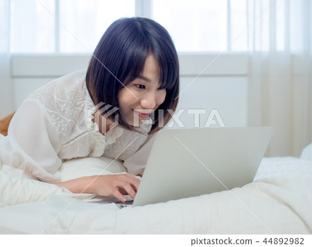 婦女在床上的操作一台計算機 婦女在床上的操作一台計算機 44892982